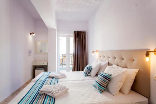 een slaapkamer met een groot bed met witte lakens en kussens bij Elychryson in Chersonissos