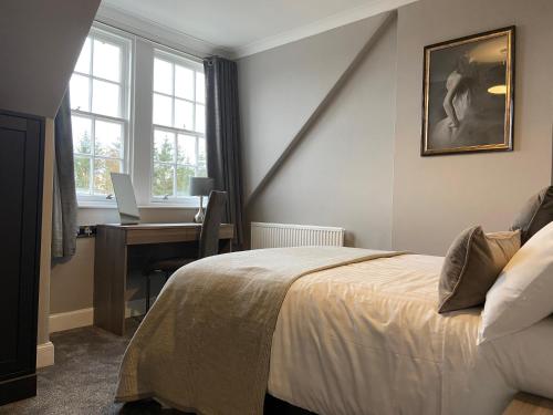 a bedroom with a bed and a desk with a laptop at Barony Castle Hotel in Peebles