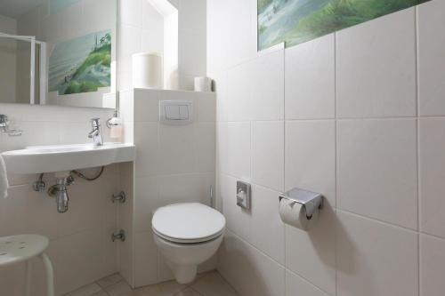 a white bathroom with a toilet and a sink at Muschel 2 in Ahrenshoop