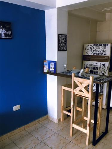 a kitchen with a blue wall and a table with a stool at FyD Apart in San Miguel de Tucumán