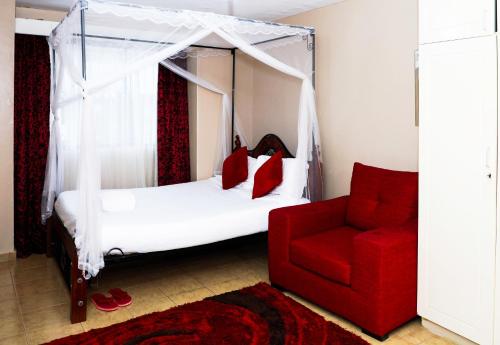 a bedroom with a canopy bed and a red chair at Martha's cozy home near JKIA airport in Nairobi