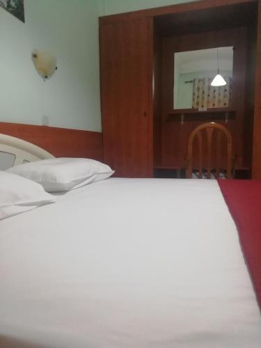 a bedroom with a white bed and a table at Hotel Elena in Edessa