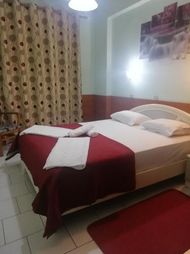 a bedroom with a large bed with red and white sheets at Hotel Elena in Edessa