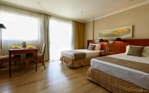 リオデジャネイロにあるPineapples BPremium - Excelentes suítesのベッド2台とデスクが備わるホテルルームです。