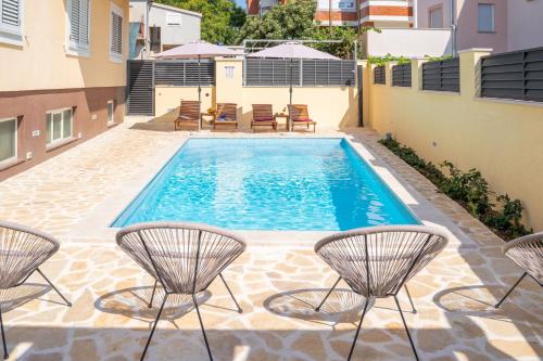 a pool with chairs and chairs on a patio at Apartments Dijana in Zadar