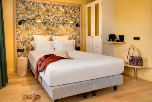 a bedroom with a large white bed with a floral wallpaper at Château Fage La Maison des Vignes - Saint-Émilion in Arveyres
