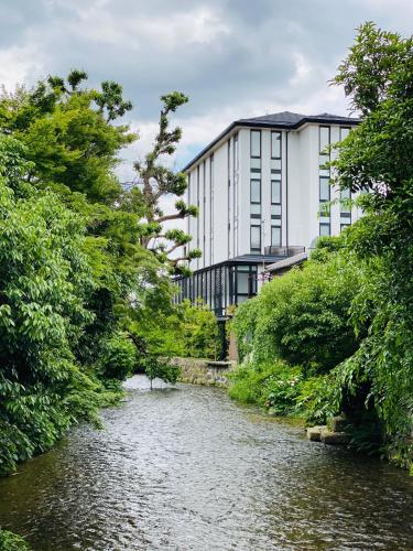 a building next to a river in front of a building at Tassel Hotel Sanjo Shirakawa in Kyoto