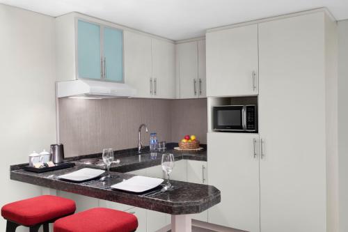 a kitchen with white cabinets and a counter with red stools at Leva Hotel and Suites, Opposite Downtown in Dubai