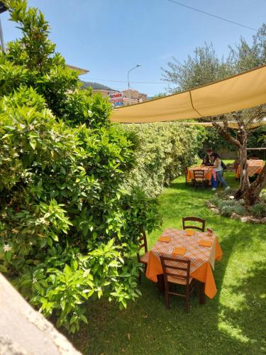 einen Tisch und Stühle unter einem Sonnenschirm in einem Garten in der Unterkunft Agriturismo Macchiapiede in Sala Consilina