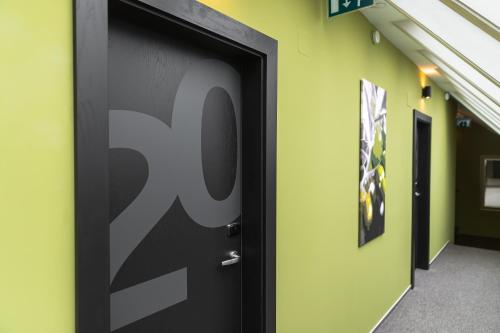 a black door with the number on a wall at Oliva Hotel in Veszprém