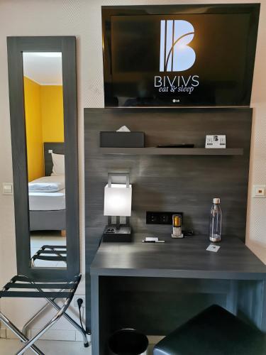 a room with a desk with a tv and a mirror at BIVIUS Hotel Restaurant Luxembourg in Luxembourg