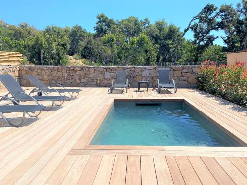 une piscine avec des chaises et une terrasse en bois dans l'établissement Villa deux chambres avec piscine chauffee proche des plages, à Sainte-Lucie de Porto-Vecchio