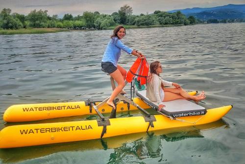 Due donne stanno cavalcando una zattera gialla sull'acqua di Ritratto sul Lago B&B a Dormelletto