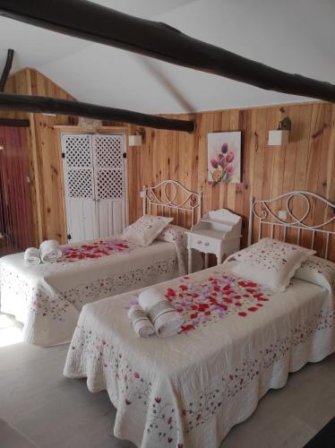 Cette chambre comprend 2 lits avec des fleurs. dans l'établissement La Casita, Apartamento Completo, à Los Navalucillos