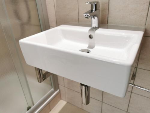 a white sink in a bathroom next to a shower at BIVIUS Hotel Restaurant Luxembourg in Luxembourg