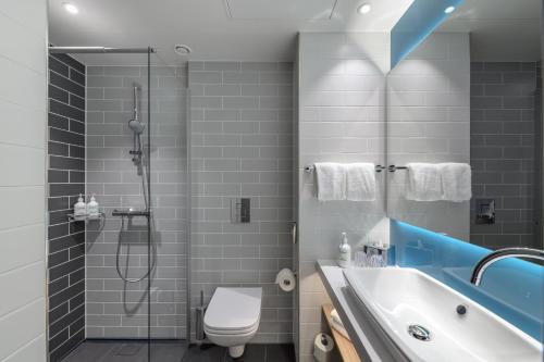 uma casa de banho com um chuveiro, um WC e um lavatório. em Holiday Inn Express - Fulda, an IHG Hotel em Fulda