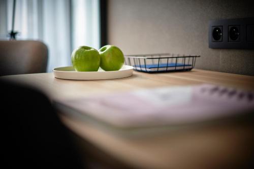 two green pears on a plate on a table at Leopold Hotel Ostend in Ostend