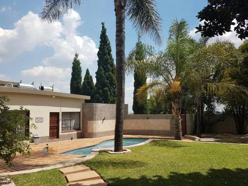 a house with a swimming pool and palm trees at Private Apartments & Biz Stays Pretoria in Pretoria