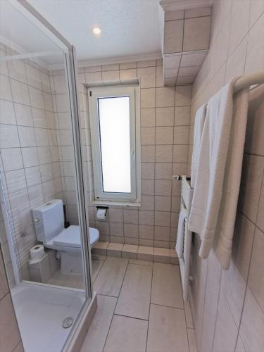a white bathroom with a toilet and a window at BIVIUS Hotel Restaurant Luxembourg in Luxembourg