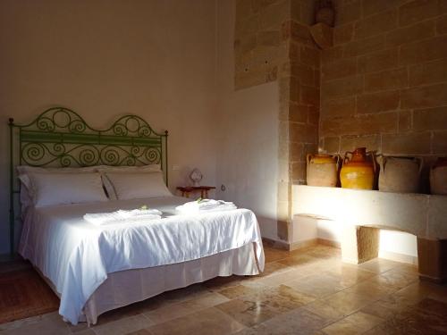 a bedroom with a bed with white sheets and vases at Giardino Frannicola in Maglie