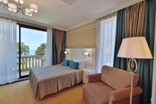 une chambre d'hôtel avec un lit, une chaise et une fenêtre dans l'établissement Dynasty Hotel, à Gelendzhik