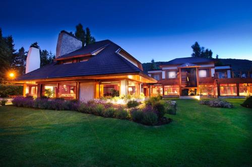 a large house with a garden in front of it at Hostería Antares Patagonia by Visionnaire in San Martín de los Andes