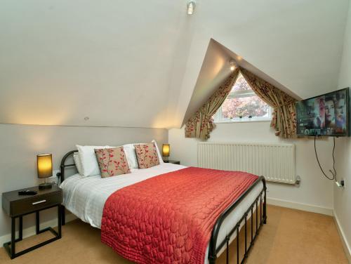 een slaapkamer met een bed met een rode deken en een raam bij School Path Ironbridge Home with Rear Terrace in Ironbridge