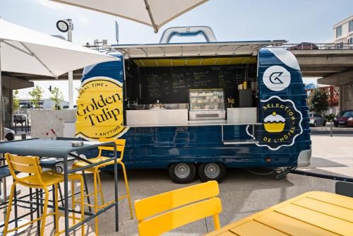 a blue food truck with yellow tables and chairs at Golden Tulip Marseille Euromed in Marseille
