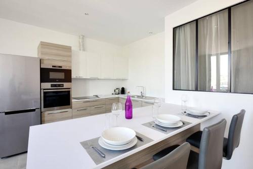 - une cuisine blanche avec une table et des verres à vin dans l'établissement LA CIOTAT - Magnifique Appartement climatisé sur le Port, à La Ciotat