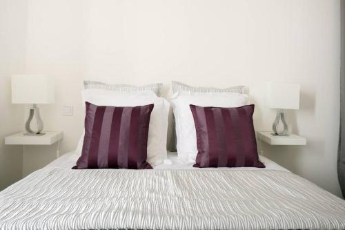 - un lit blanc avec 2 oreillers violets et 2 lampes dans l'établissement LA CIOTAT - Magnifique Appartement climatisé sur le Port, à La Ciotat