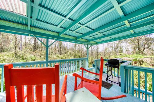 a deck with two red chairs and a blue roof at Kahu 'lo - Guardian Hawk in Volcano