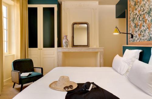 a hotel room with a bed with a hat on it at Château Fage La Maison des Vignes - Saint-Émilion in Arveyres