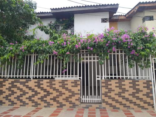 a white fence with pink flowers in front of a house at Cabaña Midas Rodadero in Santa Marta