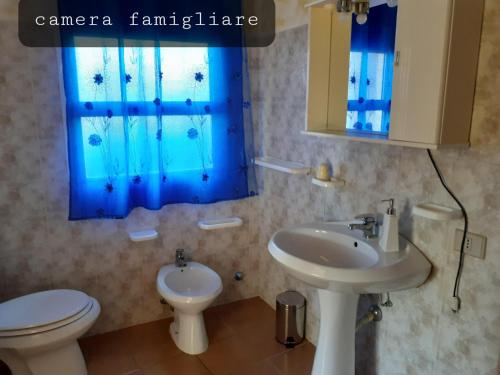 uma casa de banho com um lavatório, um WC e uma janela azul em Il Canneto em Sassari
