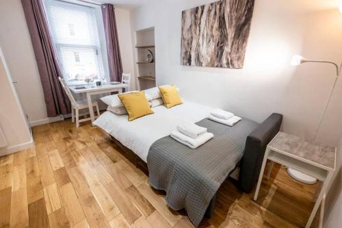 Un dormitorio con una cama con almohadas amarillas y una mesa. en ☆ New Superhost Listing- Broughty Ferry Studio ☆ en Broughty Ferry