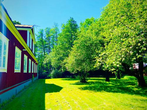 a green yard with trees next to a red building at Solakoop B&B in Karlstad