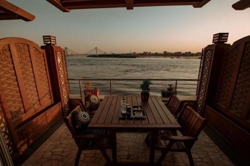 a wooden table and chairs on a balcony overlooking a river at Nile Transport Hotel in Cairo