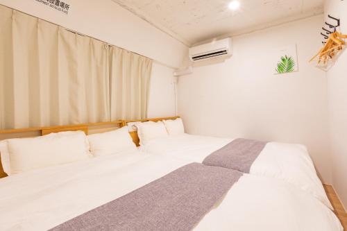 a bedroom with two white beds and a window at Feel Asakusa Stay in Tokyo