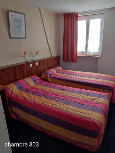 a hotel room with two beds and a window at Hotel du Commerce et de Navarre in Lourdes