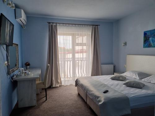 a bedroom with a bed and a desk and a window at Alba Forum in Alba Iulia