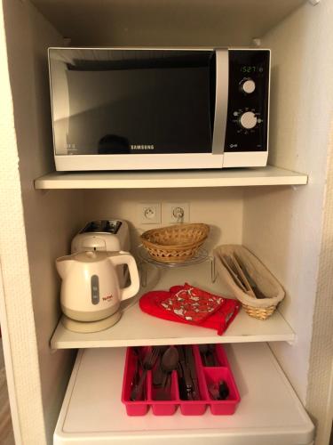 a microwave oven sitting on top of a shelf at ASTER RESIDENCE LAUREANE 1er ETAGE in Cauterets