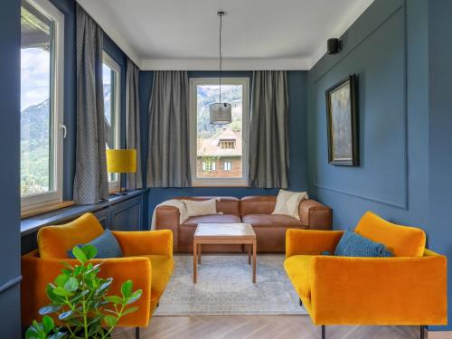 a living room with orange chairs and a couch at Das Schider - Boutique Apart-Hotel in Bad Gastein