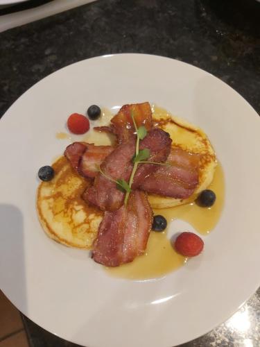 a plate of food with bacon and blueberries on it at B&Bat no3 in Market Bosworth