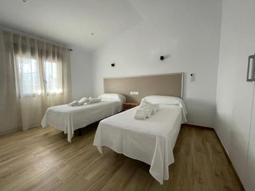 two beds in a room with white walls and wooden floors at Apartamentos Turísticos La Teja in Arroyo del Ojanco