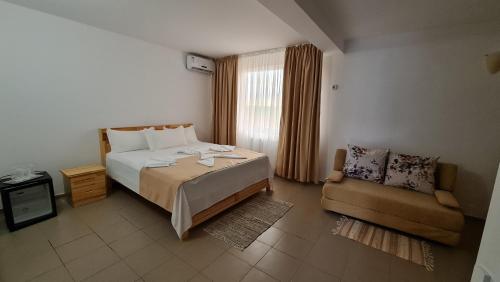 a bedroom with a large bed and a chair at Casa RBK in Vama Veche