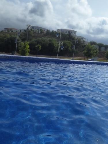 a pool of blue water with trees in the background at Appartement hôtel cabo dream in Cabo Negro