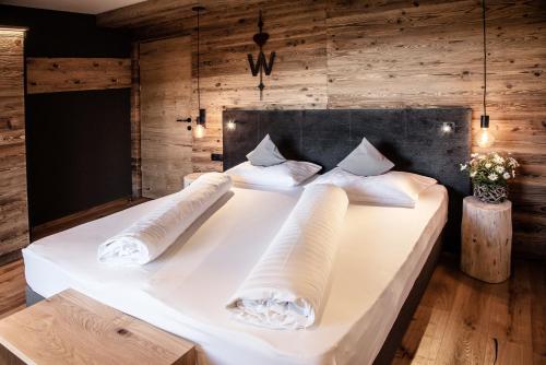 a large white bed in a room with wooden walls at Appartement- und Wellnesshotel Winkler in Falzes