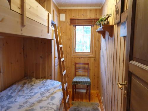 a small room with a bunk bed and a chair at Solhytta Fantastisk beliggenhet! Hytte til leie på Skrim! in Kongsberg
