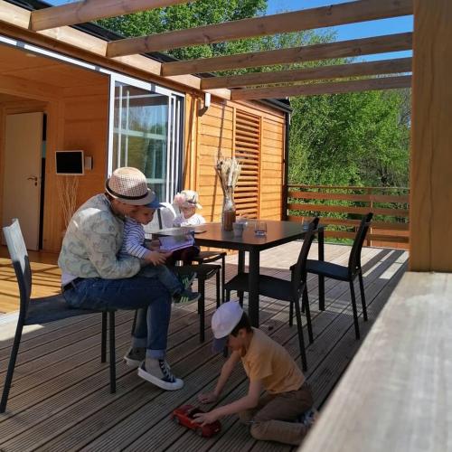 une femme et deux enfants assis à une table sur un pont dans l'établissement LE PRE DE L AIR, à Saint-Michel-Mont-Mercure