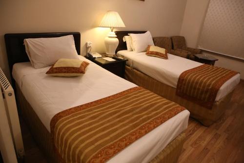 a hotel room with two beds and a couch at Carlton Tower Hotel Lahore in Lahore